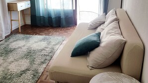Een gezellige woonkamer met een beige bank, een klein rond tafeltje en een houten vloer.