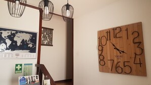 Een kamer met een houten wandklok, een wereldkaart en een trap.