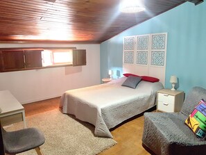 A bedroom with a bed, a desk, a chair, a nightstand, and decorative wall panels.