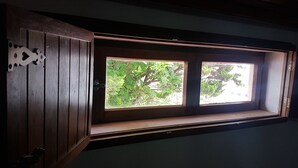 Een kamer met een houten deur en een raam met uitzicht op groen.