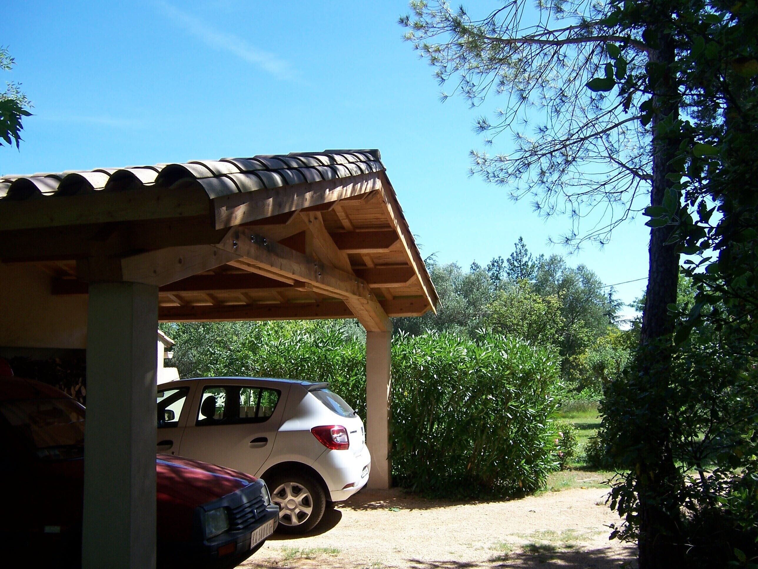 A covered carport with a white car parked underneath.
