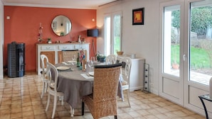 Een eethoek met een ronde tafel, witte stoelen en een grote spiegel. Op de tafel staan potplanten en een waterdispenser.