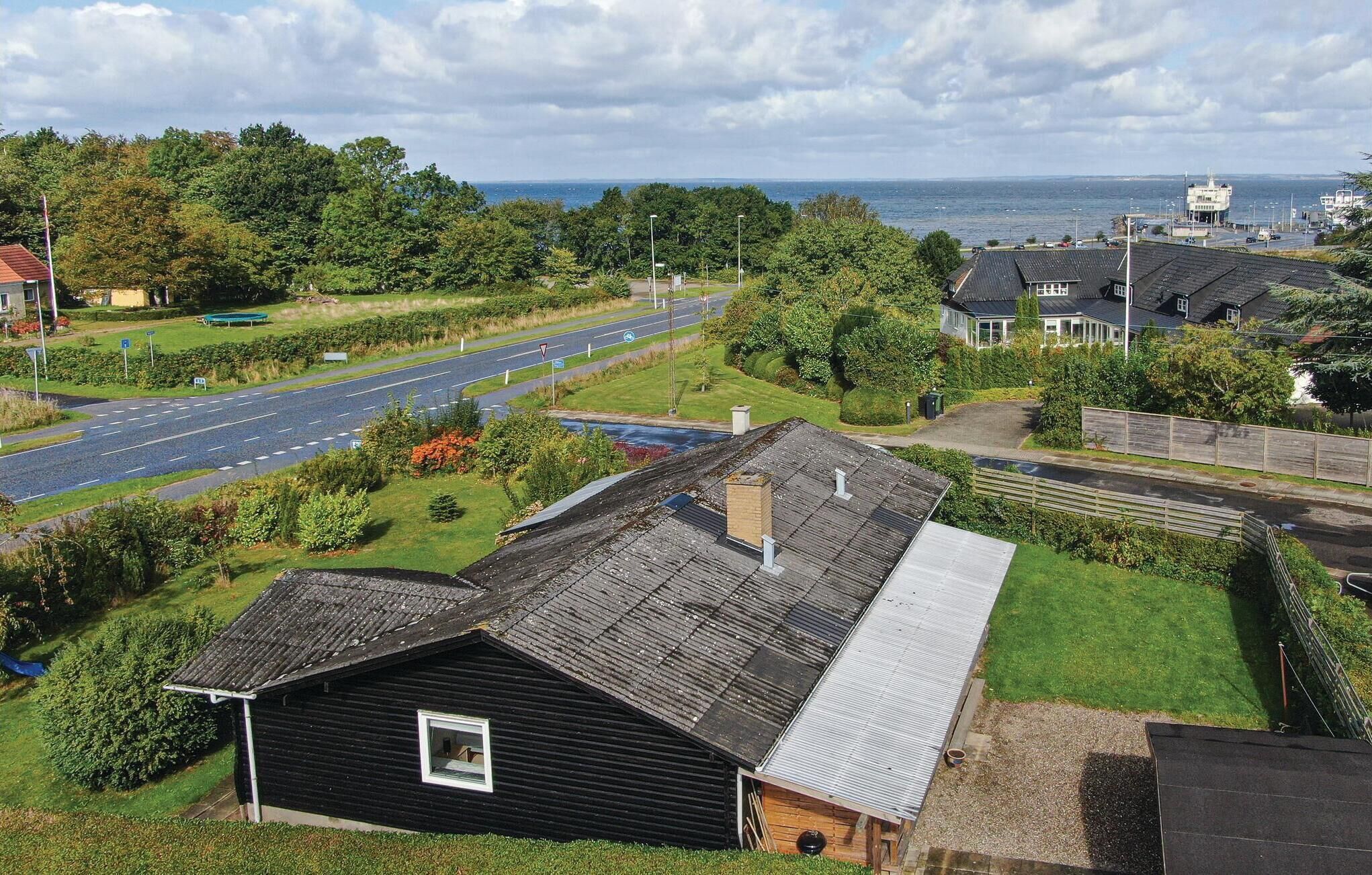 A residential area with a road, green spaces, and a view of the sea.
