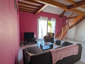Un salon avec un canapé, une table basse, un téléviseur et un escalier.