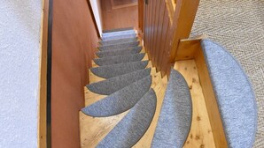A wooden staircase with a unique spiral design and a carpeted landing.