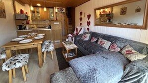 A cozy cabin interior with a dining area, sofa, and kitchen.