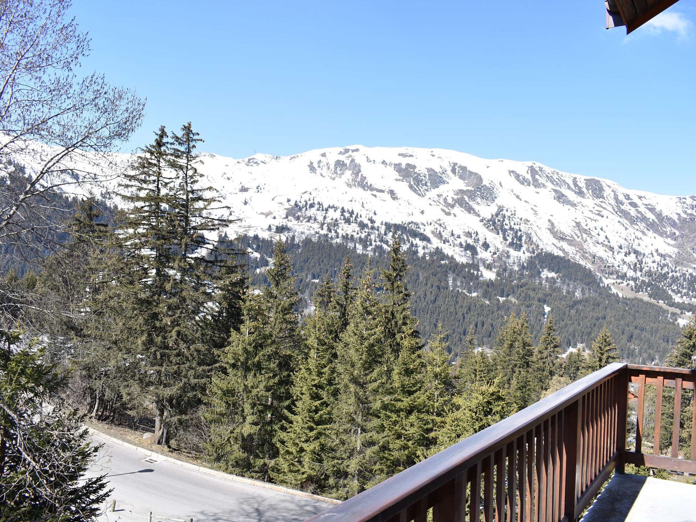 A mountain view with a wooden deck overlooking a road and dense forest.