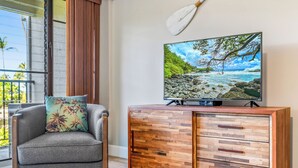 A modern living room with a gray sofa, a wooden cabinet, and a television displaying a scenic beach view. - GORGEOUS REMODEL-WELL EQUIPPED-MODERN LUXURY-AC THROUGHOUT (Kihei)