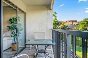 Un balcon avec une table et une chaise en verre, une plante en pot et un panier en osier.