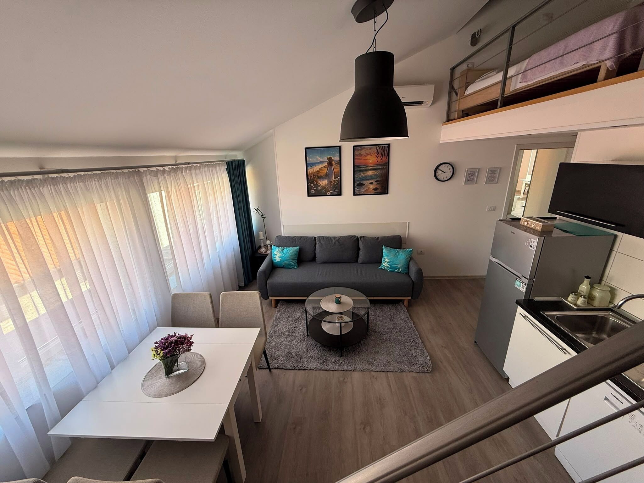 Un espacio habitable compacto con sofá, mesa de comedor y kitchenette.