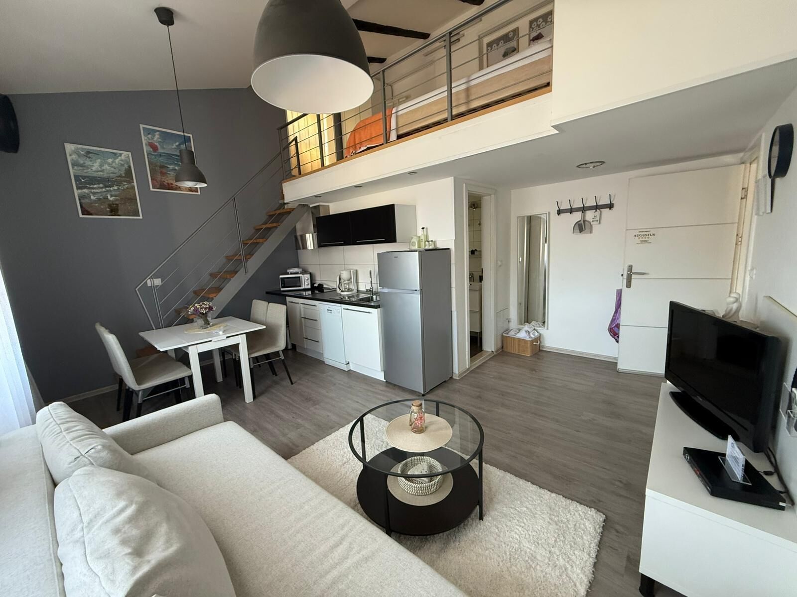 A modern apartment with a dining area, kitchen, living room, and a balcony.