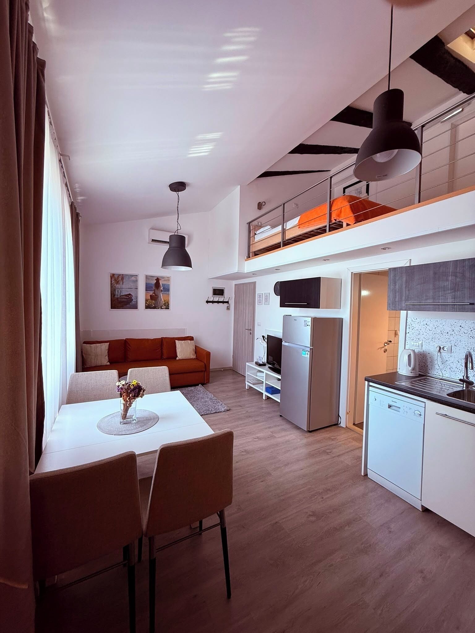 Un ambiente compatto con zona pranzo, angolo cottura e camera soppalco con balcone.