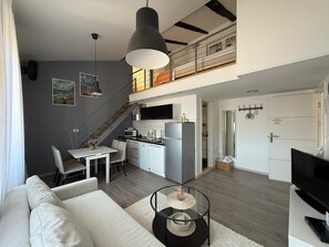 Un apartamento moderno con comedor, cocina, sala de estar y una escalera a un nivel superior.