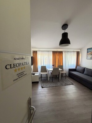 Ein modernes Wohnzimmer mit Essbereich, einer Couch, einem Tisch und einer Chandelier.