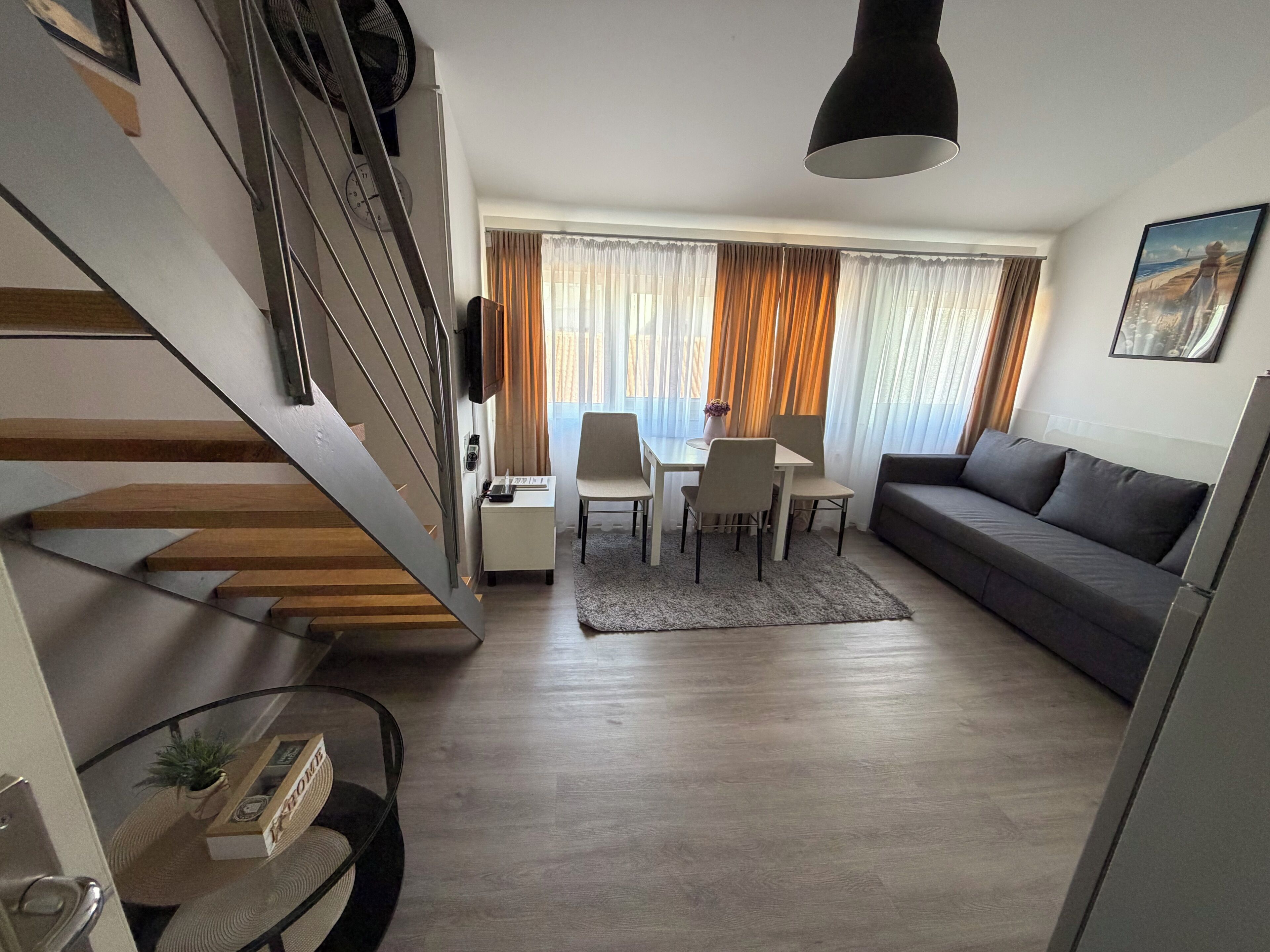 A modern living room with a staircase, a dining area, and a sofa.