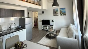 Un apartamento moderno con cocina, comedor y sala de estar. Cuenta con un dormitorio estilo loft con cama.