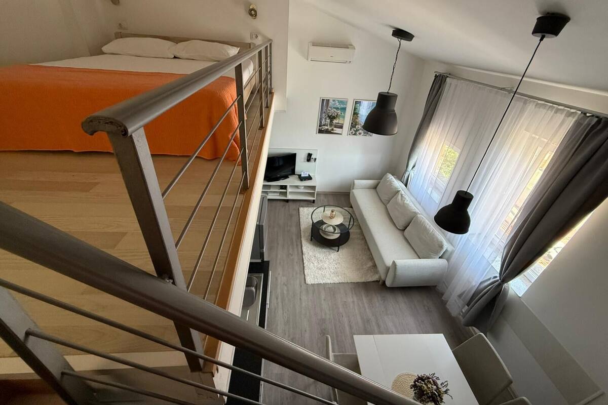 A modern apartment with a balcony, a sofa, a dining table, and a bed.