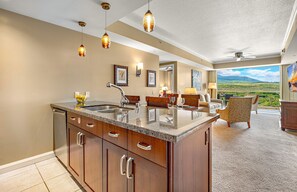 A spacious kitchen with a large island, a dining area with a view, and a ceiling fan.