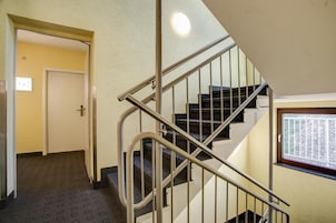 A staircase with metal railings and carpeted steps leading to a landing.