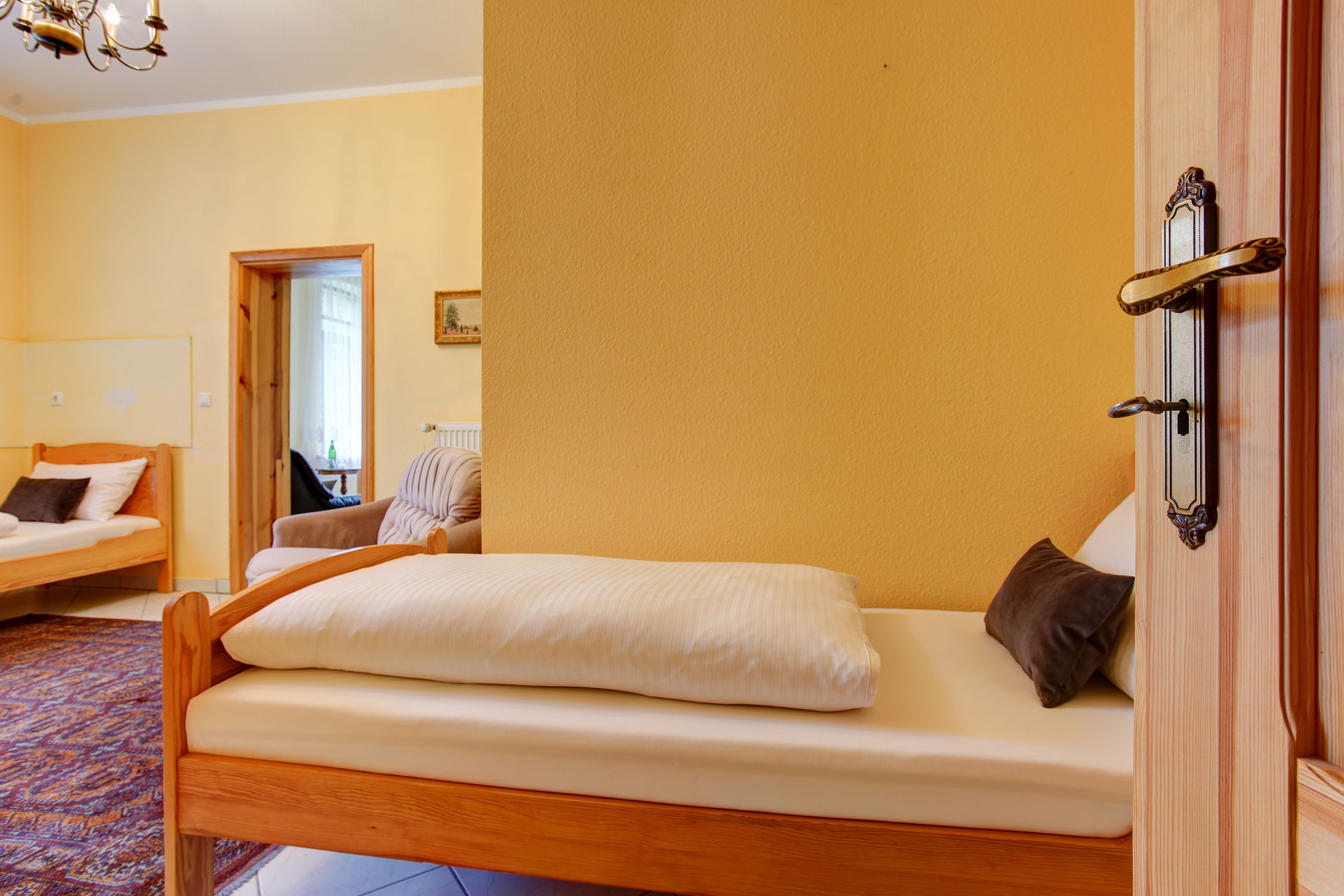 Una camera da letto con un letto di legno, una sedia e una porta con maniglia.