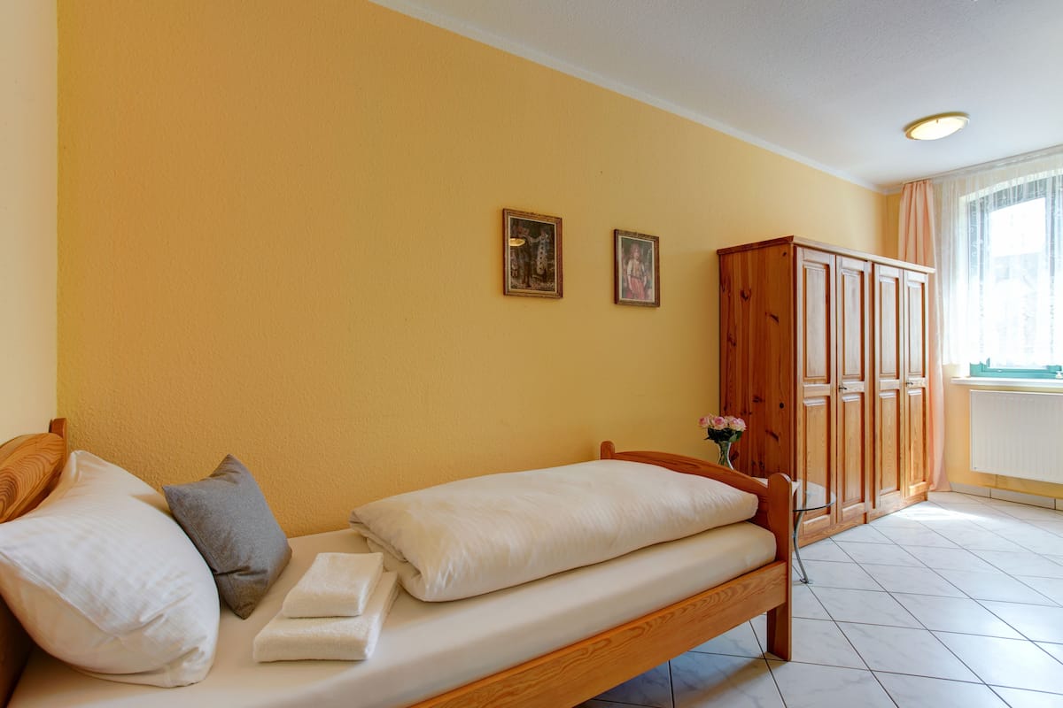A bedroom with a wooden bed, a wardrobe, and two framed pictures on the wall.