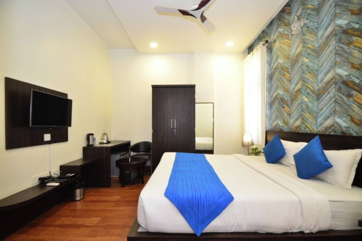 A hotel room with a bed, a desk, a chair, a television, and a ceiling fan.