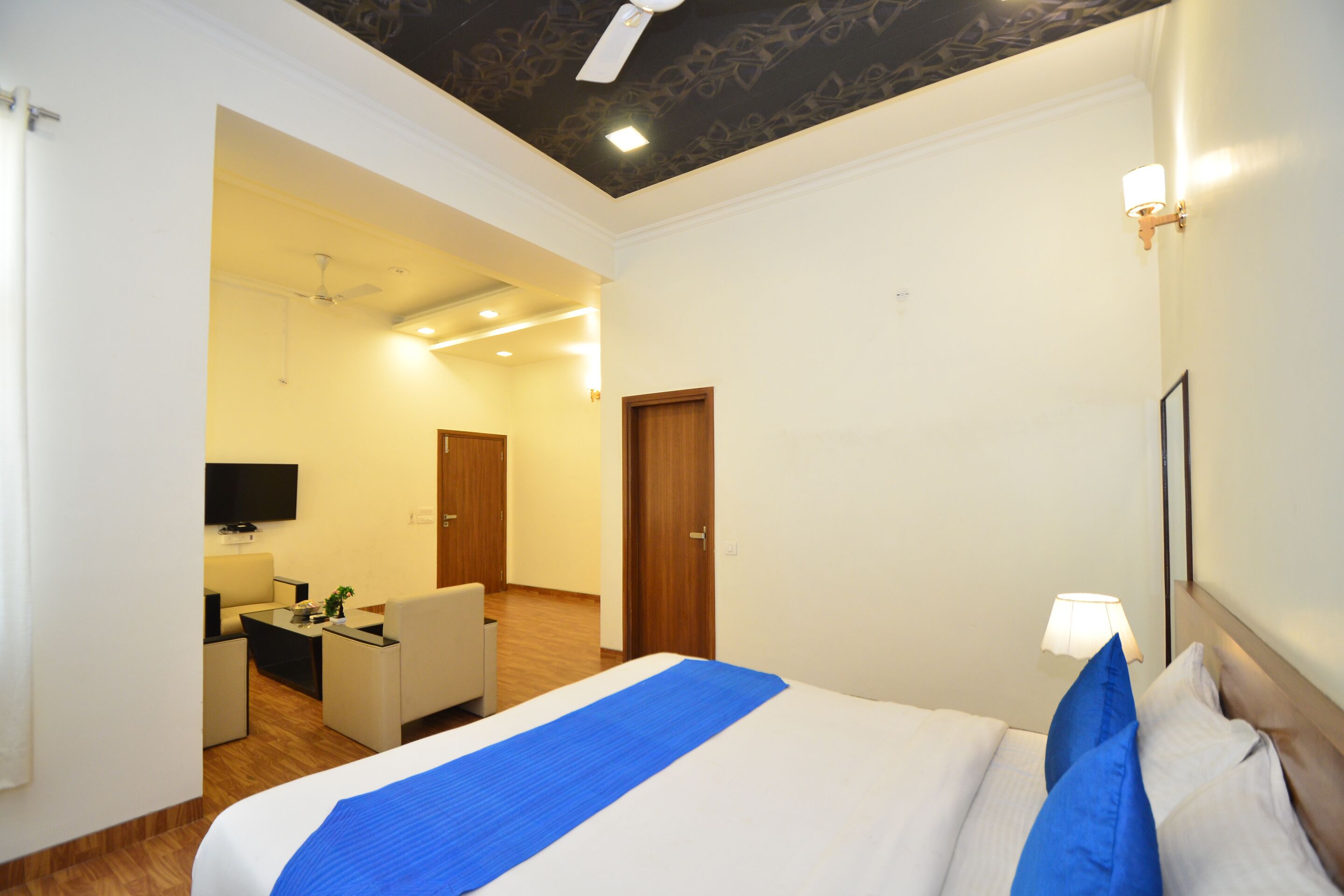 Una habitación de hotel con cama, escritorio, silla, televisor y puerta.