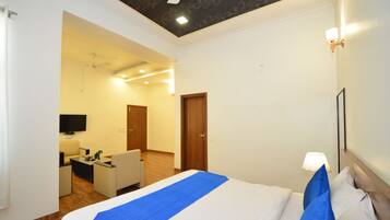Una habitación de hotel con cama, escritorio, silla, televisor y puerta.