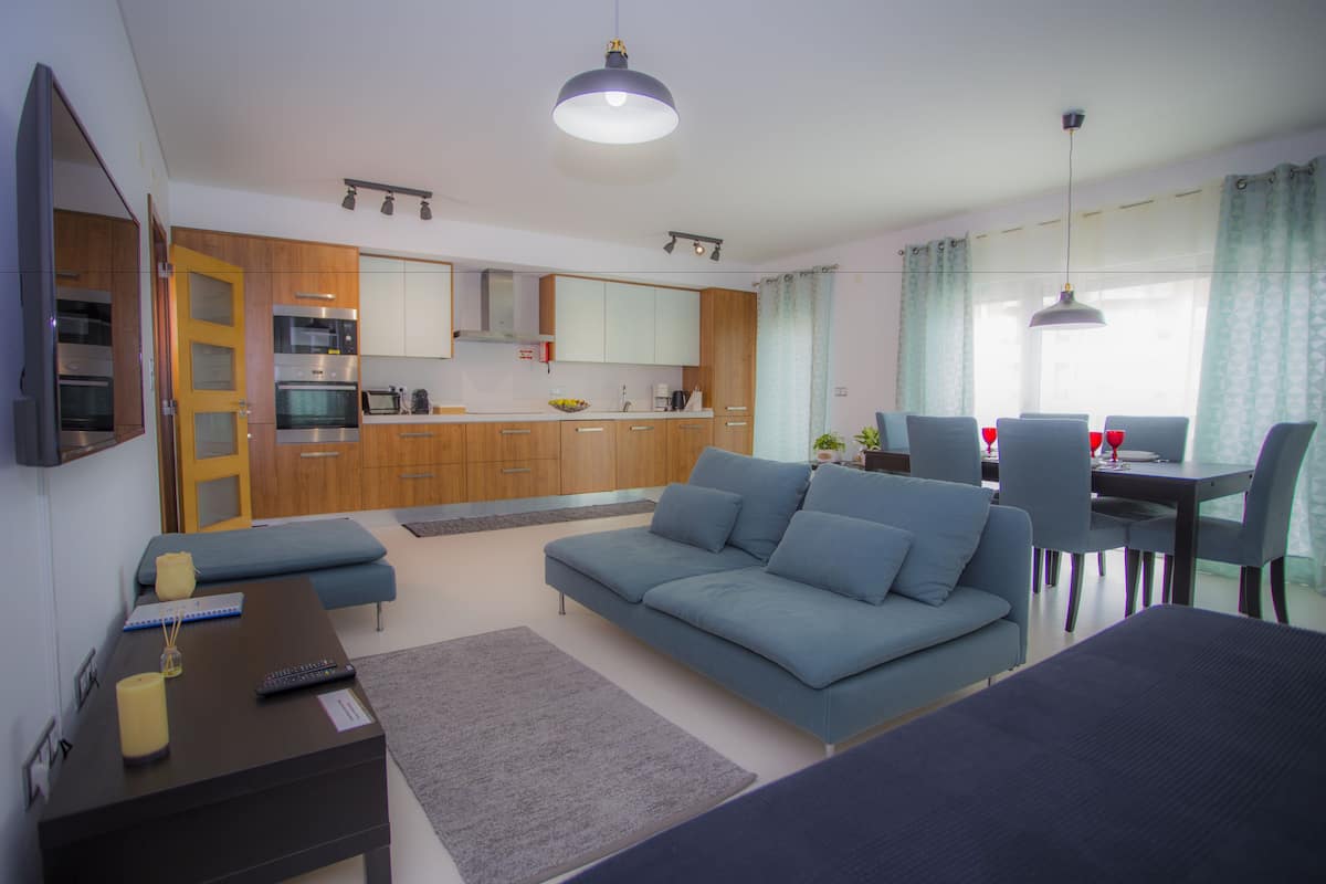 A modern living room with a sofa, a coffee table, and a dining area with chairs and a table.