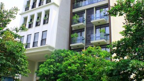 A multi-story building with balconies, a parking area, and a tree in front. - Lake House Studio (Hanoi)