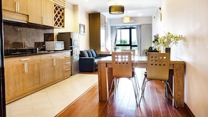 A modern kitchen with wooden cabinets, a dining table with chairs, and a view of the living area. - Lake House Studio (Hanoi)