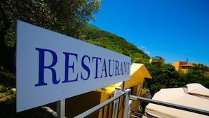 Señal de restaurante con vista a una colina y edificios al fondo.