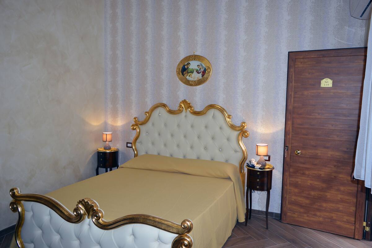 Ein Schlafzimmer mit einem großen Bett, zwei Nachttischen, einer Holztür und einem Wandbild.