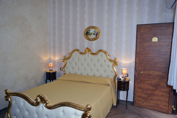 A bedroom with a large bed, two bedside tables, a wooden door, and a wall-mounted picture. - Villa Catiè (Gragnano)