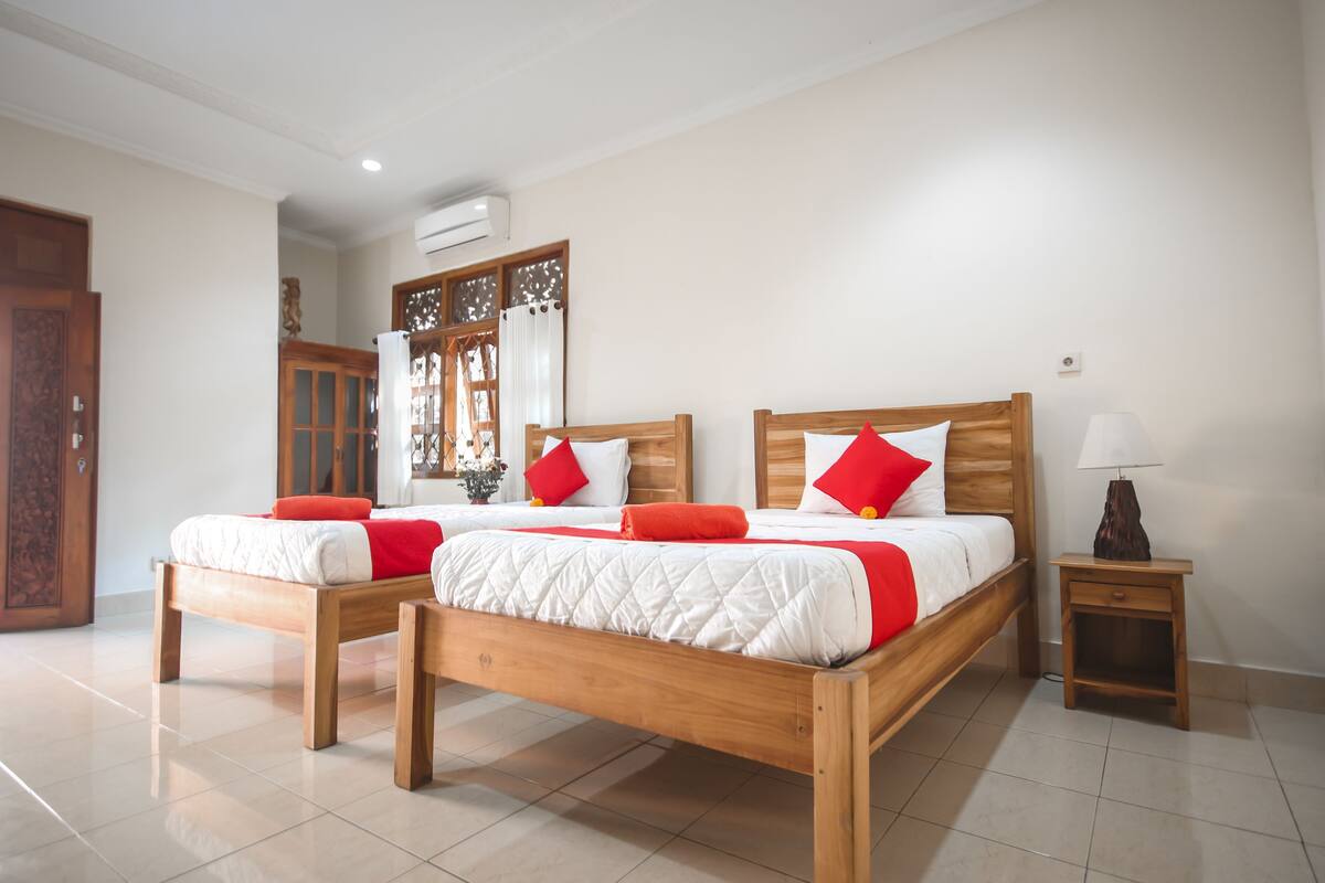 Una cama doble con cabecera y piecera de madera, dos mesitas de noche y una mesita auxiliar con lámpara.