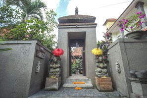 A temple entrance with a statue at the top, surrounded by greenery and a building with a balcony. - Satya House Ubud (Ubud)