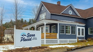A two-story house with a porch and a sign for Sara Placid Inn & Suites. - Sara Placid Inn & Suites (Saranac Lake)