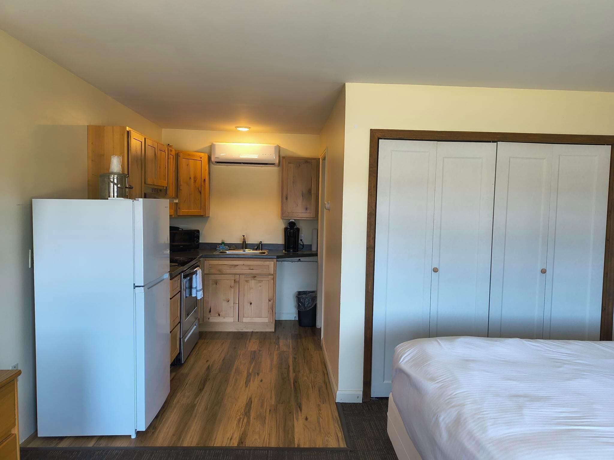 Una habitación de hotel pequeña con kitchenette, una cama y un armario.