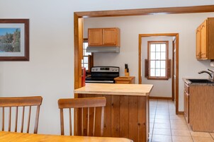 A kitchen with wooden cabinets, a stove, and a window.