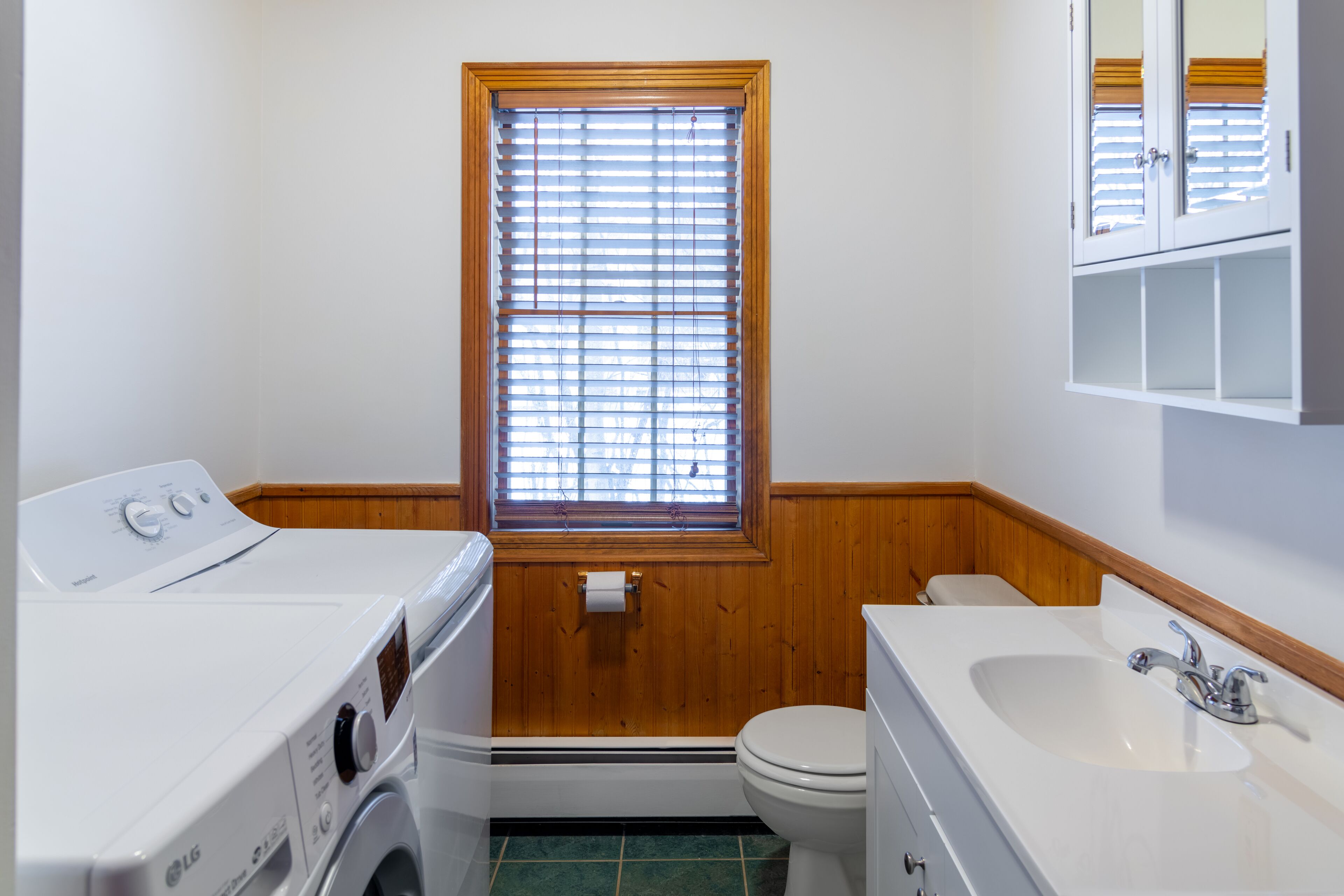 A compact bathroom with a washing machine, toilet, and sink.