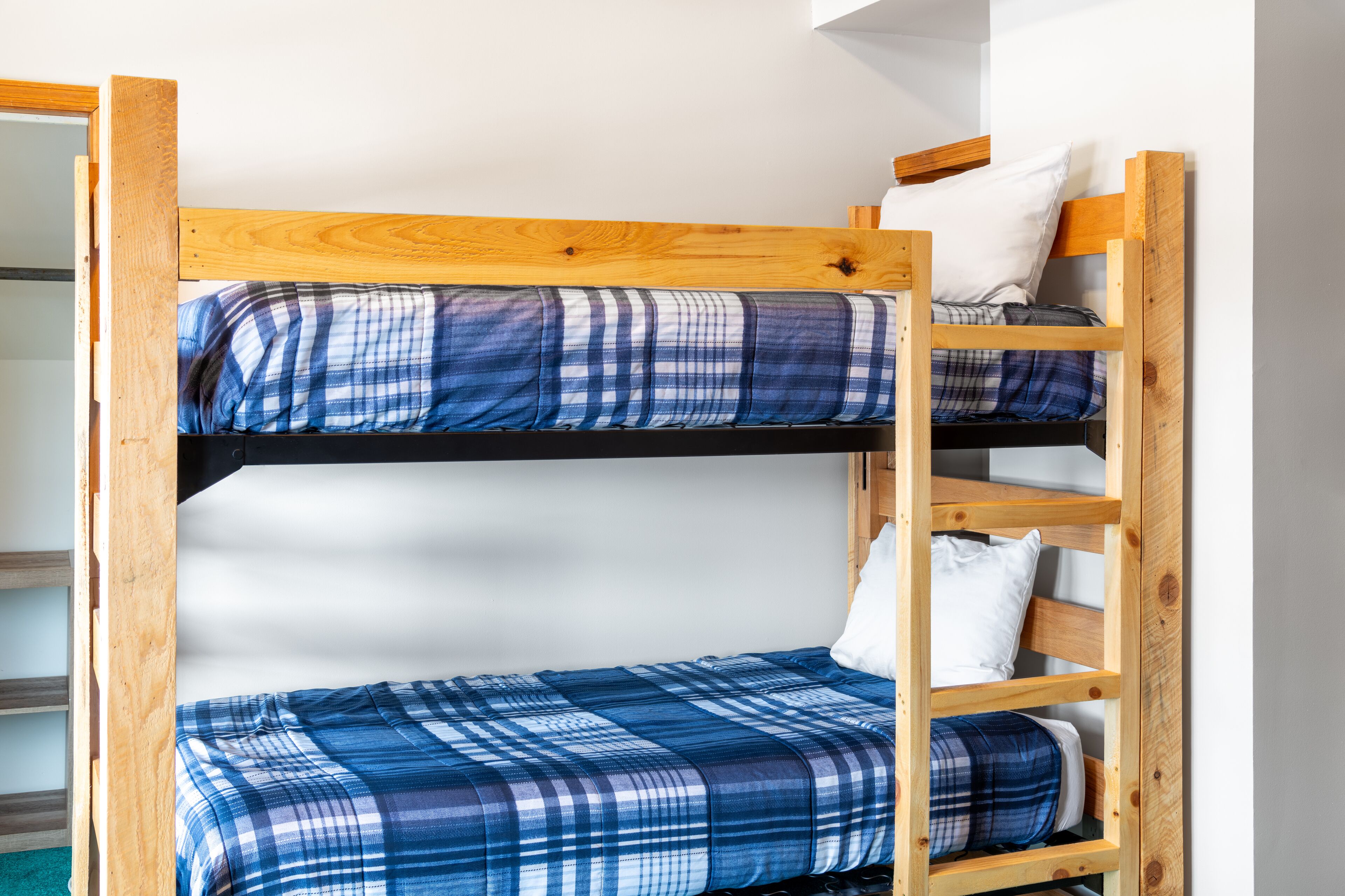 Una cama litera con colchón estampado en cuadros y estructura de madera.