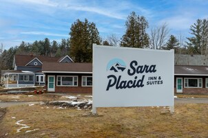 A sign for Sara Placid Inn & Suites with a view of the building in the background.