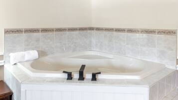 Un baño en esquina con una bañera independiente, una toalla al lado y un borde decorativo de azulejos.