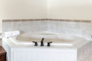 Un baño en esquina con una bañera independiente, una toalla al lado y un borde decorativo de azulejos.