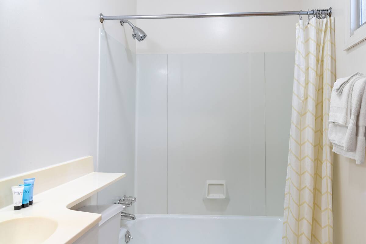 A bathroom with a bathtub, a shower, and a toilet. There are toiletries on the counter.
