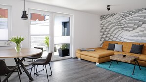 Uma sala de estar moderna com um sofá, uma mesa de centro e um espaço de jantar com cadeiras e uma mesa.