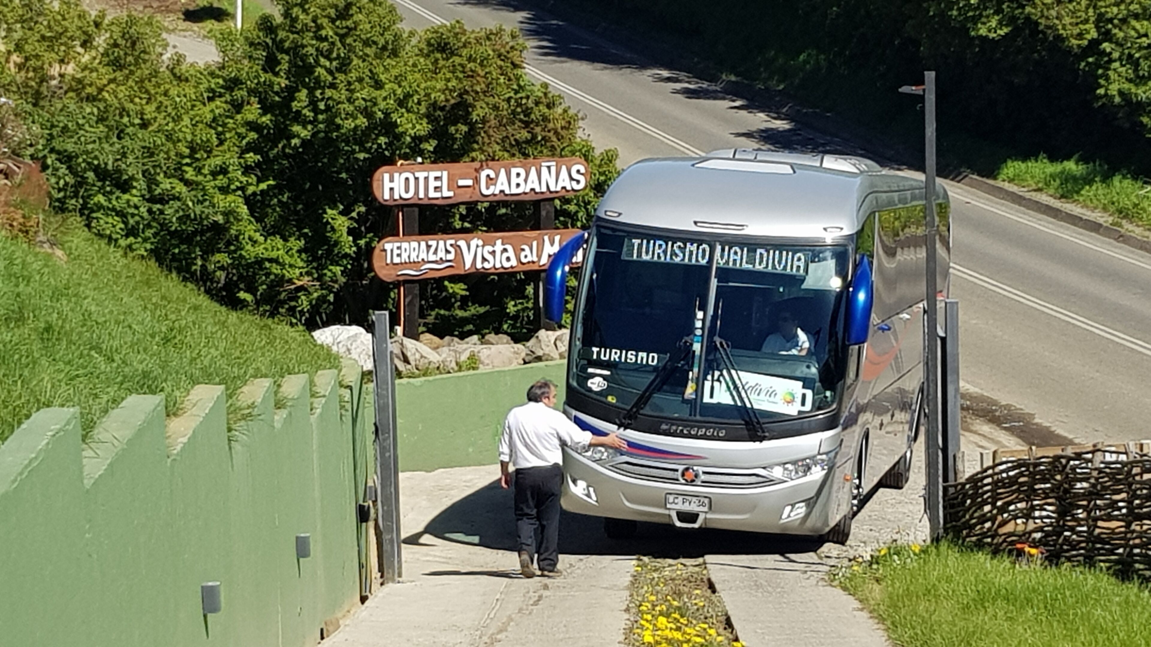 Un autobus sur lequel on peut lire l’inscription « TURISMO VALDIVIA », et un homme qui se tient à côté.