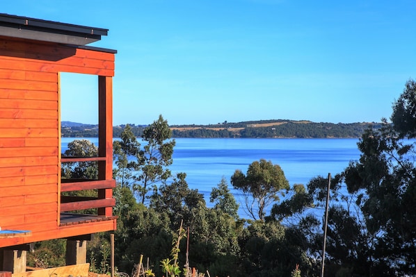 A wooden cabin with a balcony overlooking a lake.