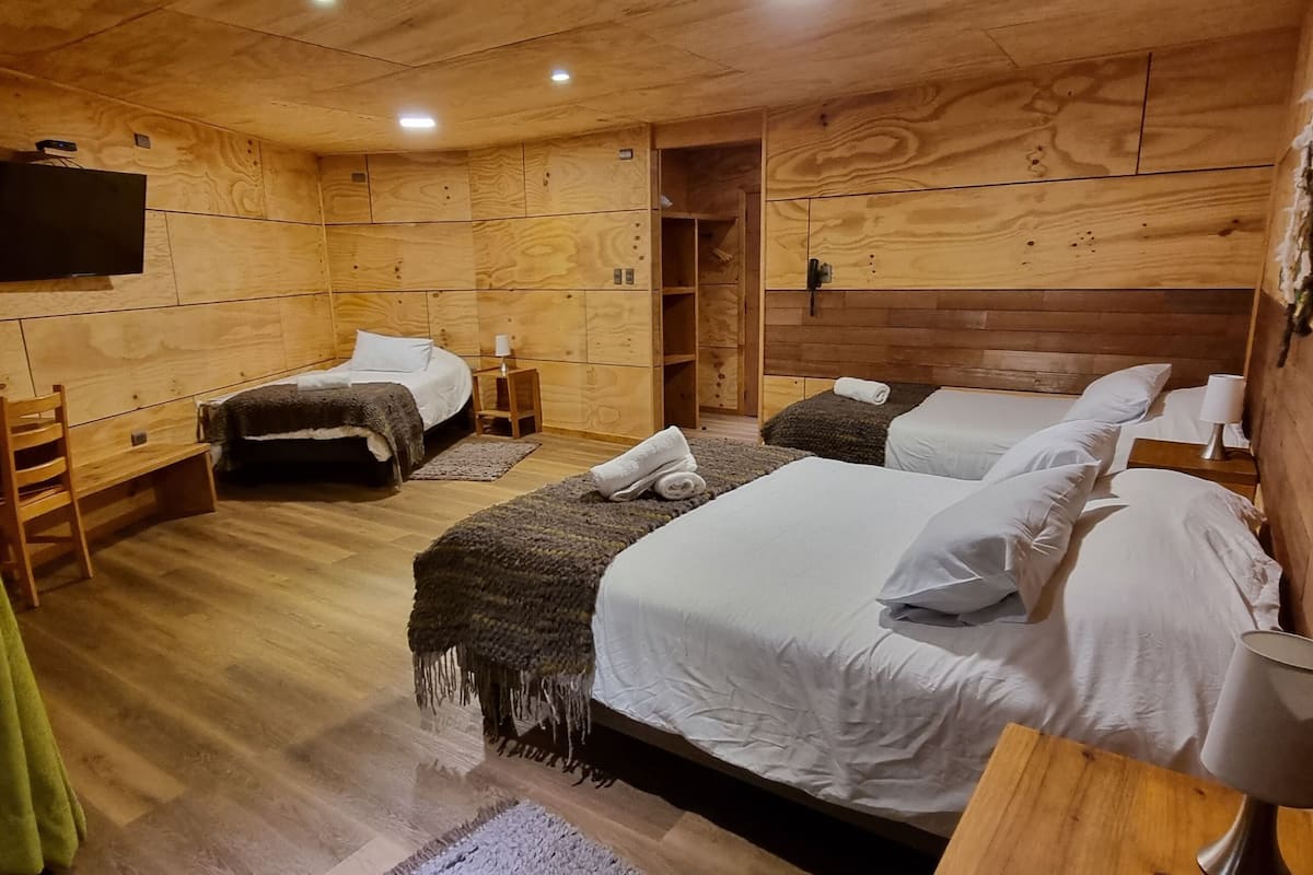 Una habitación tipo cabaña de madera con dos camas, un televisor y un armario de madera.