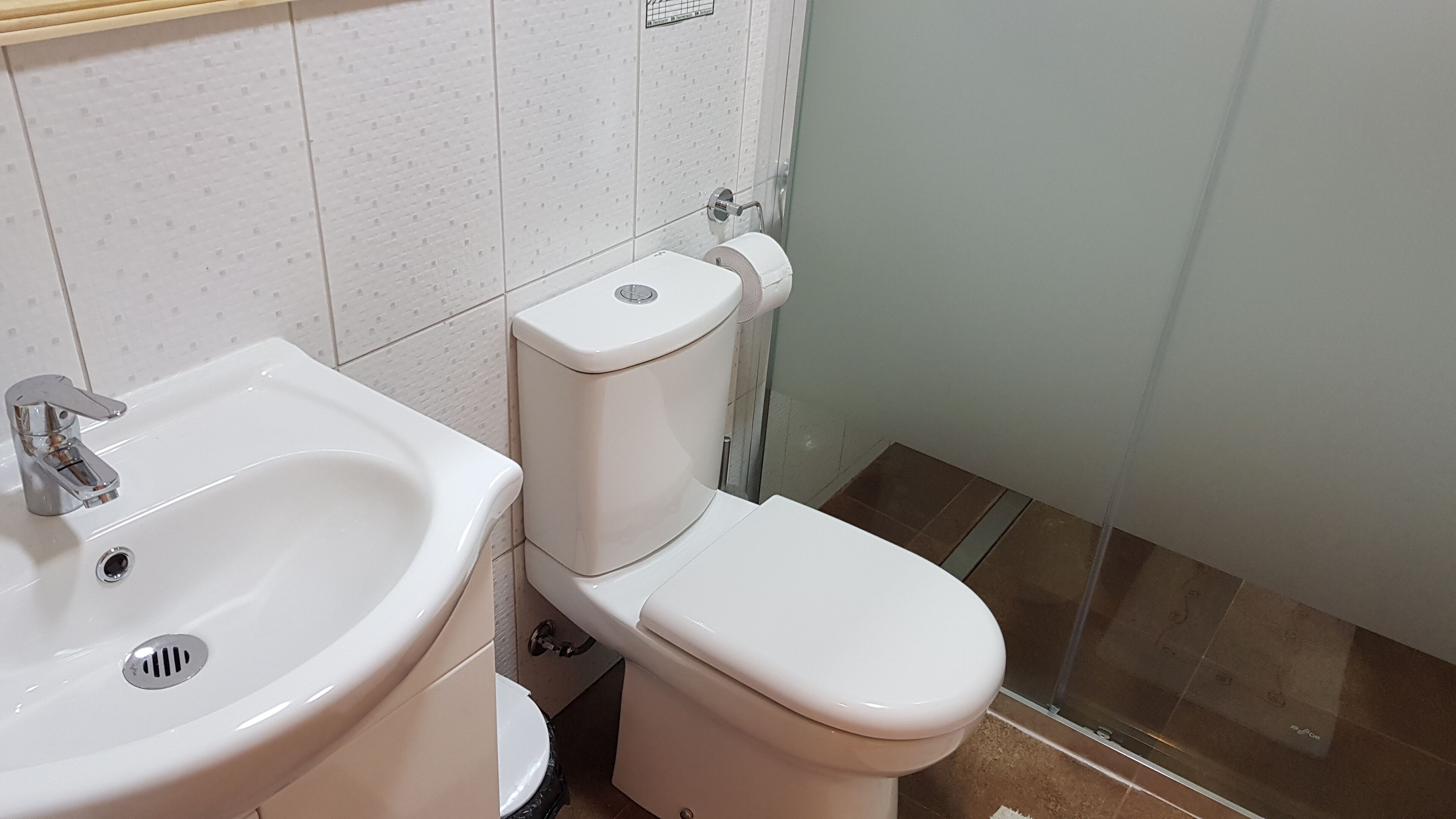 Een badkamer met een wit wastafel, toilet en douche.